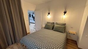 Ein Schlafzimmer mit einem gemusterten Bettbezug, zwei Wandlampen und einem Holzboden.