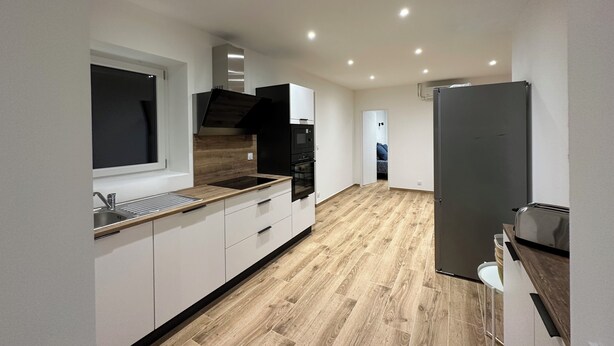 Eine moderne Küche mit weißen Schränken, einer Holz Arbeitsplatte, einem eingebauten Backofen und einer schwarzen Dunstabzugshaube.
