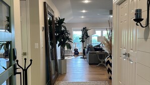 A hallway with a patterned rug, wooden flooring, a door with a coat rack, and a wall-mounted lamp. - Beautiful and relaxing Golf & Lake retreat waiting just for you!!  (Hot Springs Village)