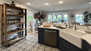 A modern kitchen with a central island, wooden shelves, and a view to the outside. - Beautiful and relaxing Golf & Lake retreat waiting just for you!!  (Hot Springs Village)