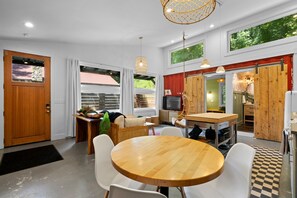 A modern kitchen with a dining area, wooden cabinets, and a large window.