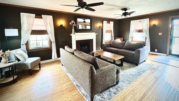 A living room with a fireplace, two sofas, a coffee table, and a ceiling fan.