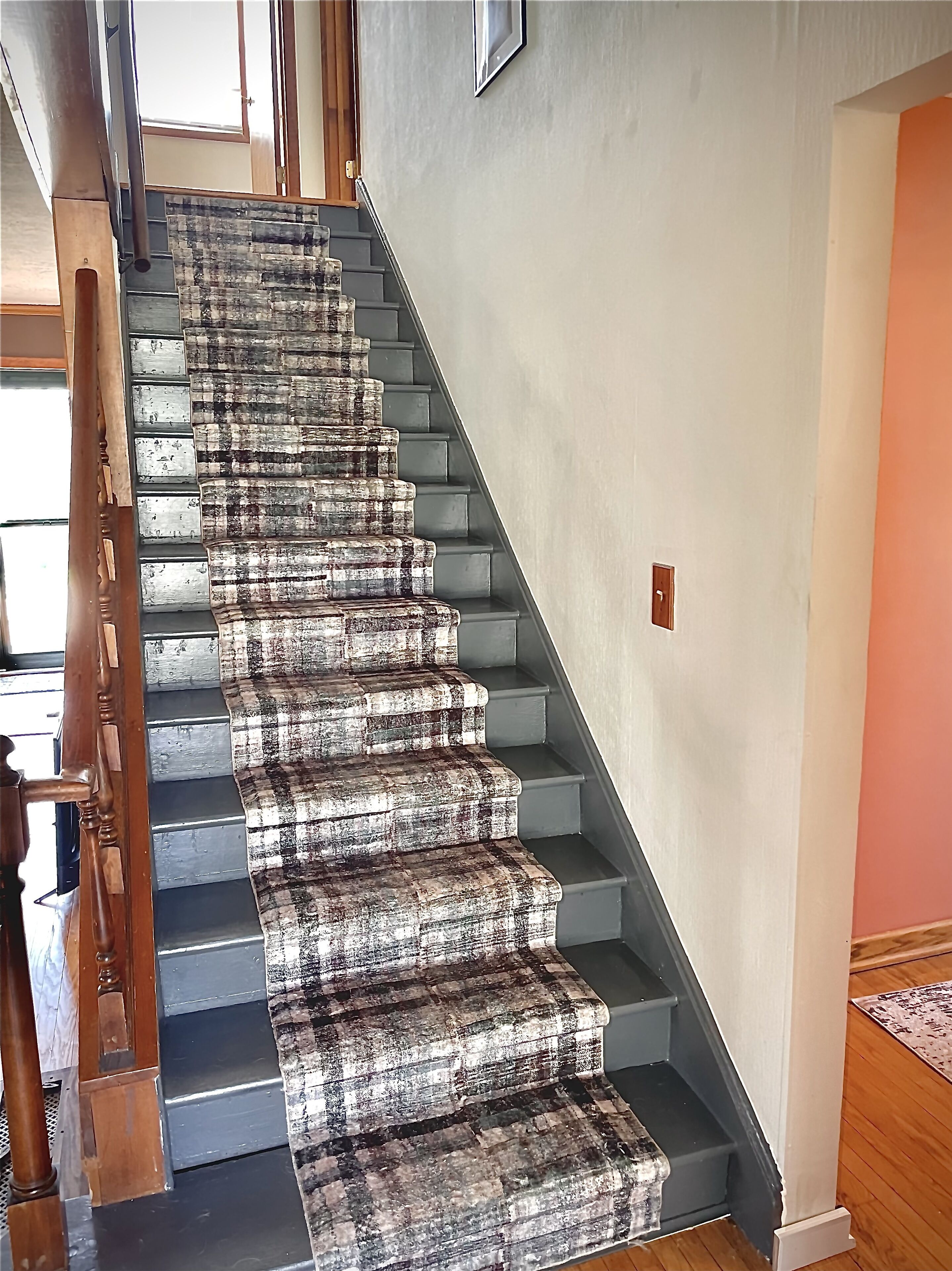 A staircase with a unique patterned carpet and wooden handrail.