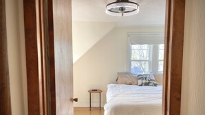 A bedroom with a bed, a small table, and a window.
