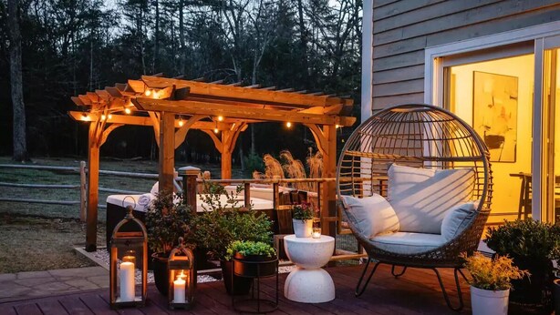 A wooden deck with a hanging chair, lanterns, and potted plants.