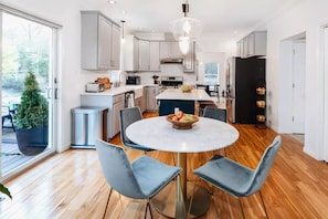Una cocina moderna con una mesa redonda, armarios grises y una isla grande con fregadero.