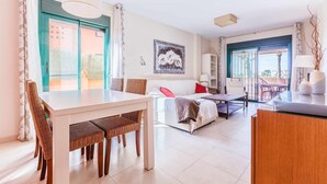 Een moderne woonkamer met een eethoek, een bank, een salontafel en een groot raam met uitzicht.