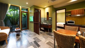 A hotel room with a dining area, a bathroom, and a view of greenery. - Hotel Chiem Hoian (Da Nang)