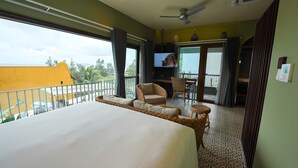 A hotel room with a large bed, a balcony with wicker furniture, and a television. - Hotel Chiem Hoian (Da Nang)