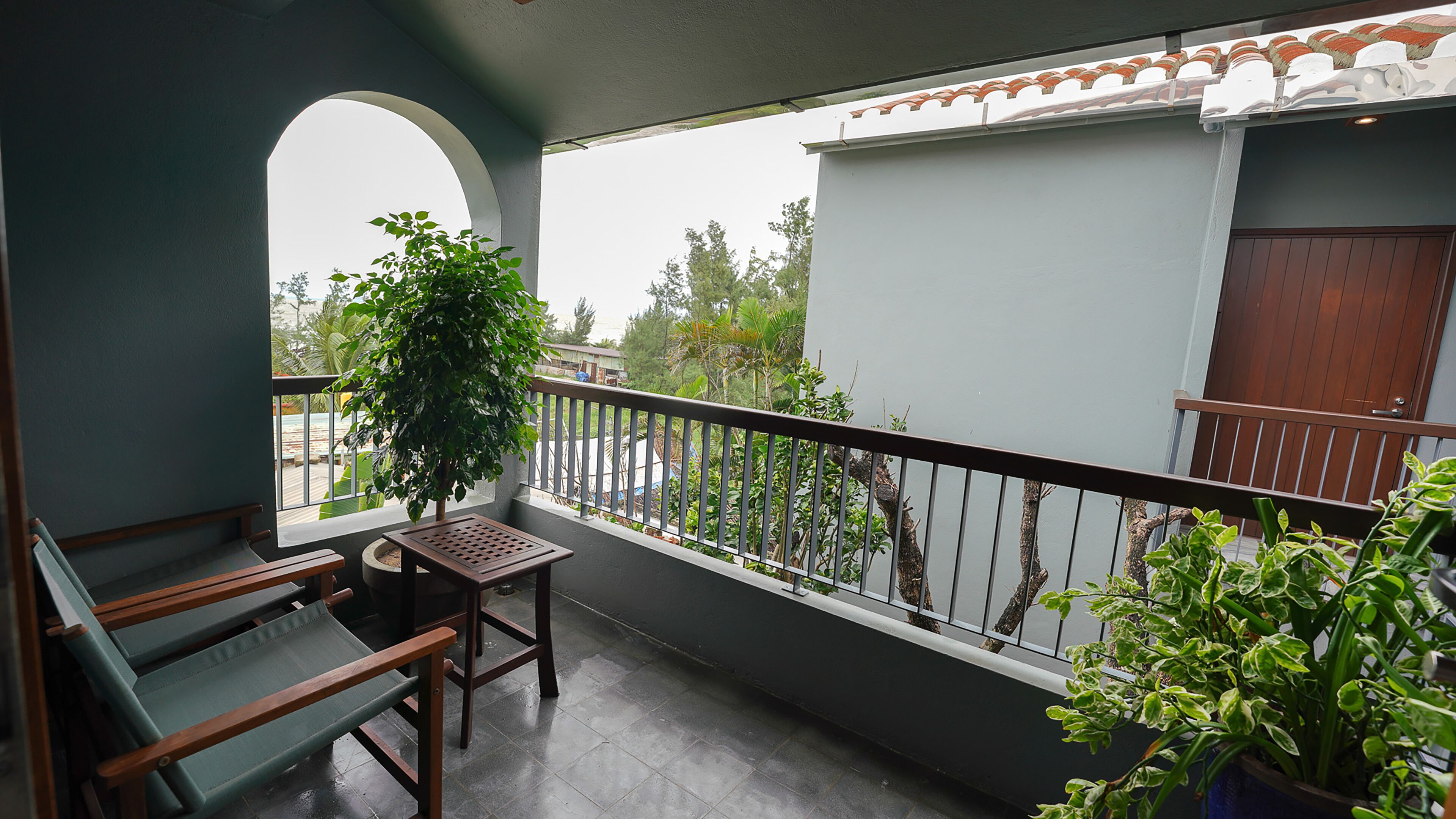 A balcony with a wooden bench, a potted plant, and a view of the street.