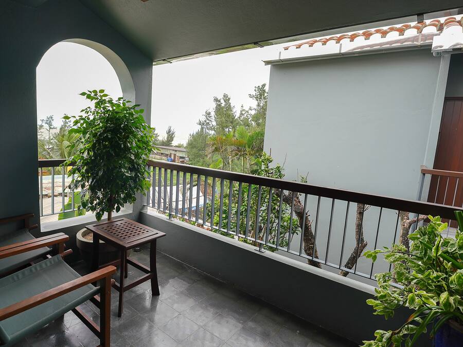 A balcony with a wooden bench, a potted plant, and a view of the street.