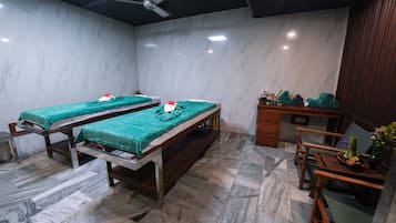 Two comfortable beds with green linens and small tables for personal items.