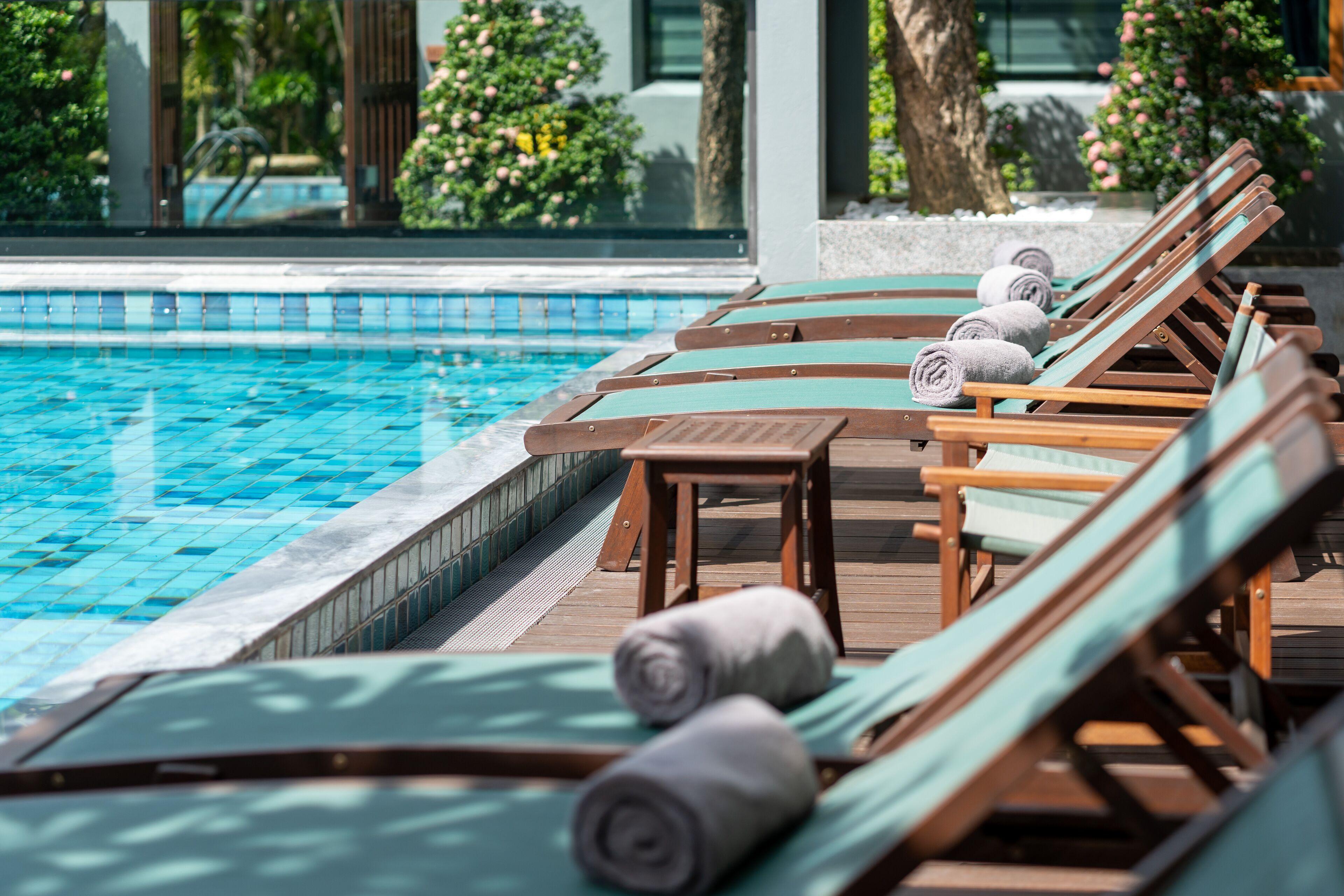 A poolside area with wooden lounge chairs and a tiled pool.