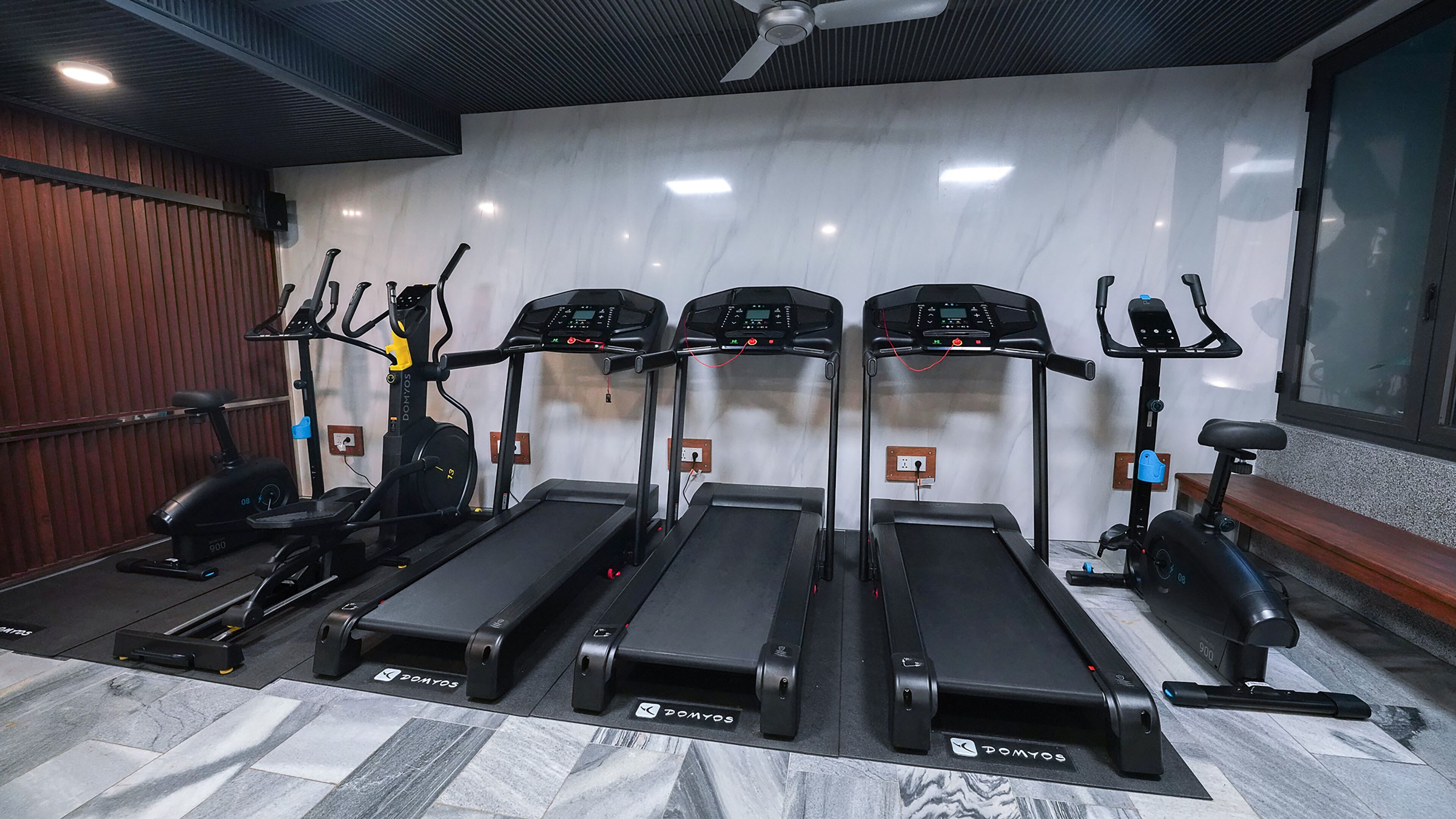 A gym with four treadmills, a stationary bike, and a bench.