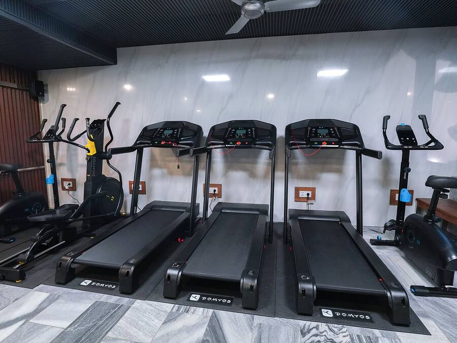 A gym with four treadmills, a stationary bike, and a bench.