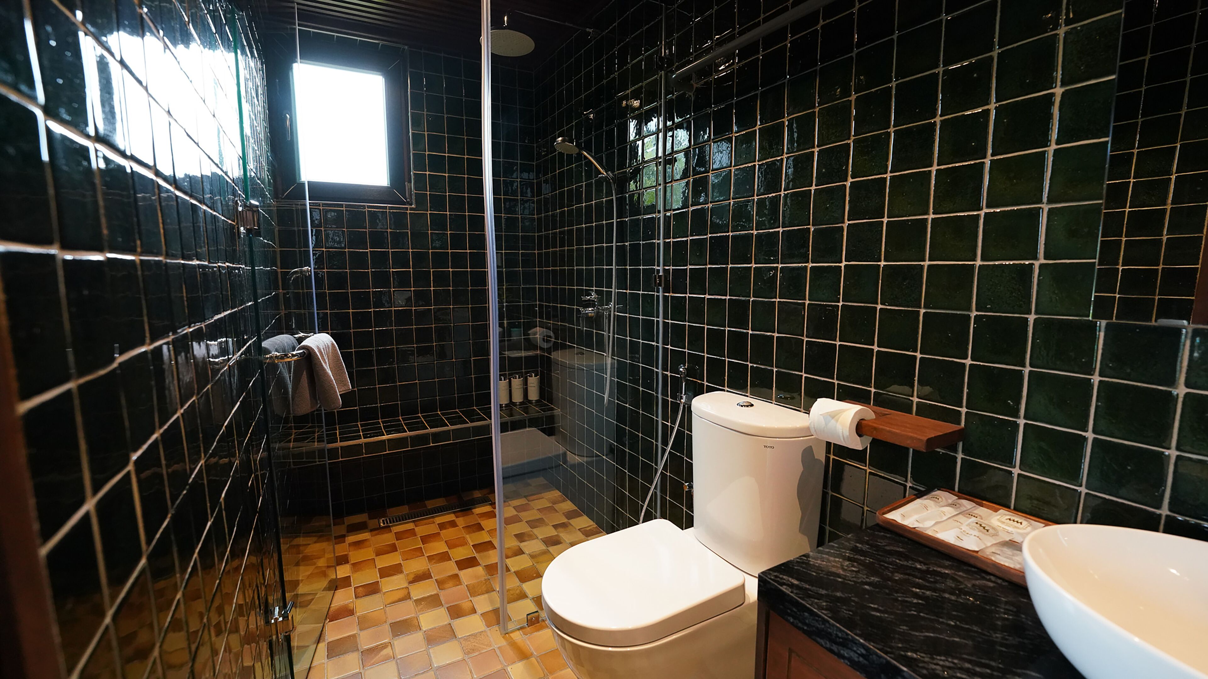 Ein Badezimmer mit Schachbrettboden, Toilette, Dusche und Waschbecken.