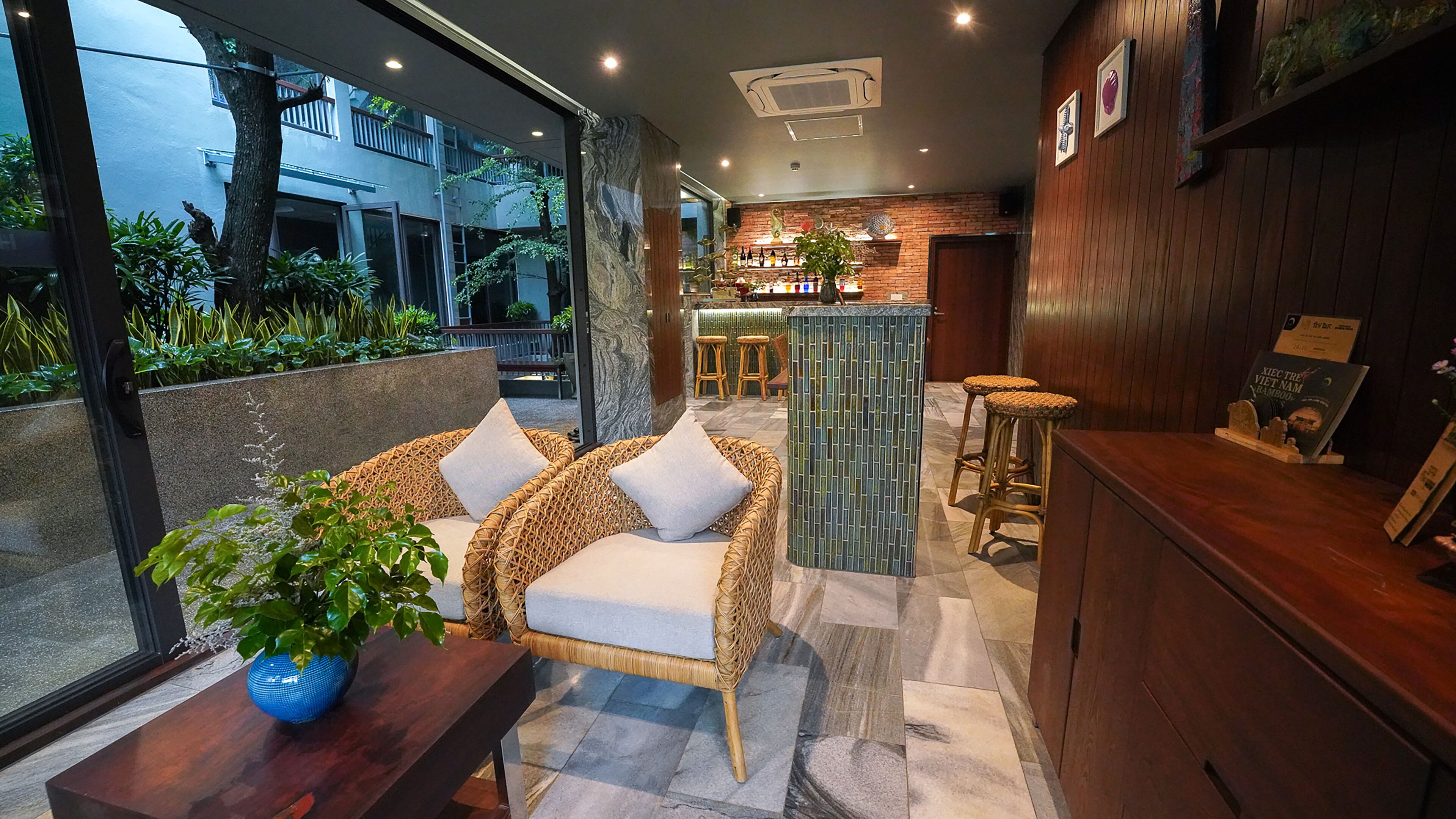 A modern bar area with wicker furniture, a bar counter, and a seating area with a view of the outside.