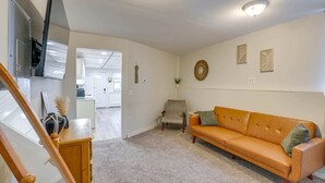 Una sala de estar con un sofá, un sillón, un mueble de madera y una escalera.