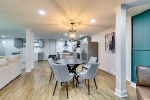 A modern living room with a dining area, kitchen, and a teal accent wall.