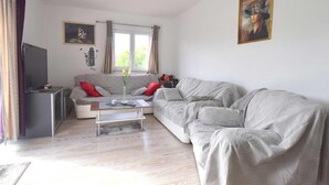 A living room with a grey sofa, a coffee table, and a television on a stand. - Apartment Letizia with two bedrooms (Rasopasno)