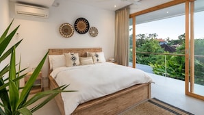 A bedroom with a large bed, a wooden headboard, and a view of greenery outside.