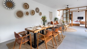 A modern dining area with a wooden table set for six, surrounded by wooden chairs.
