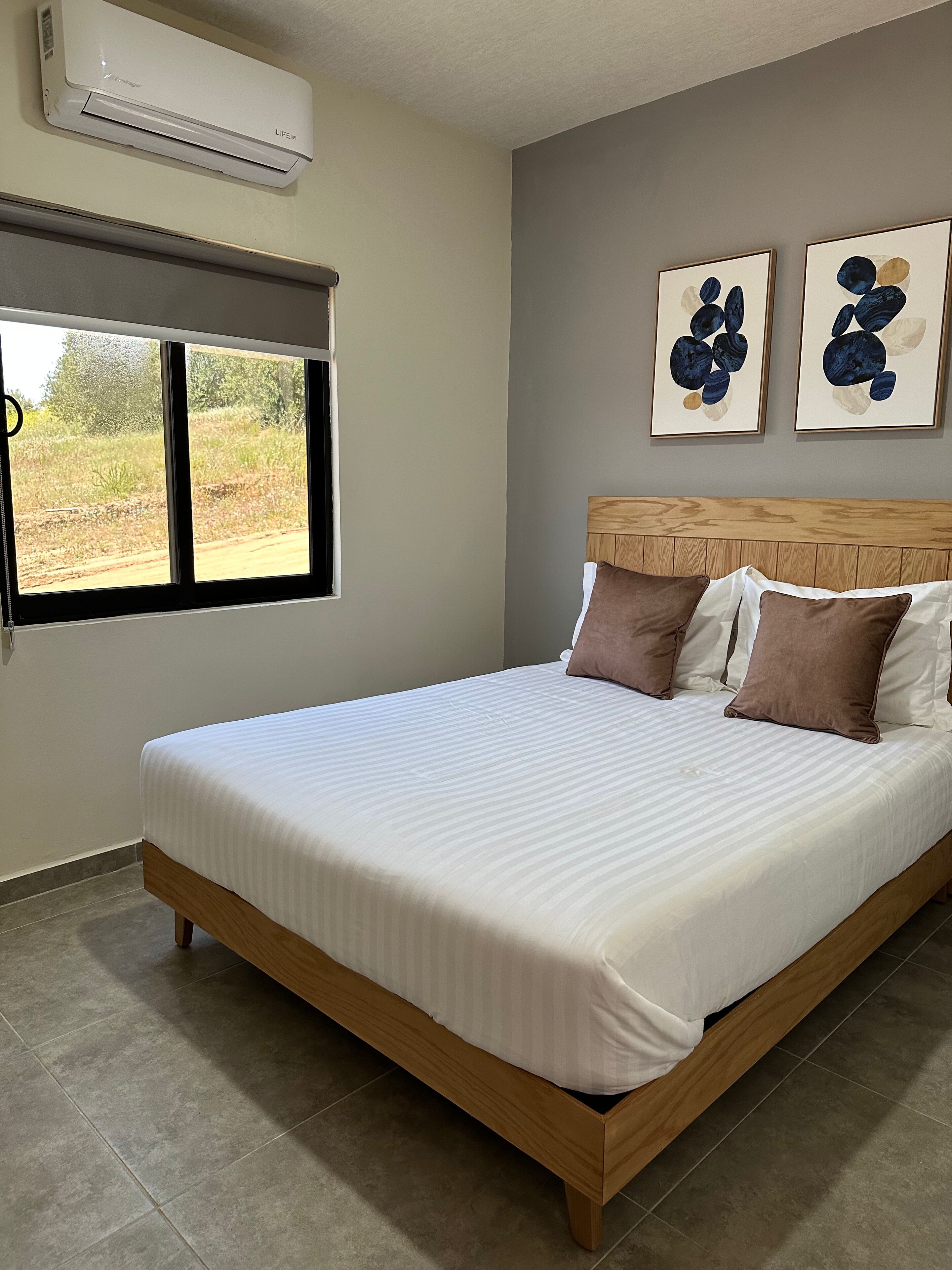 Une chambre à coucher comprenant un lit, une fenêtre et deux œuvres d’art accrochées au mur.