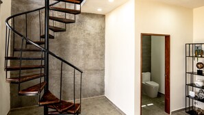 Un interior moderno con una escalera en espiral, un baño a la vista y un pequeño rincón de descanso.