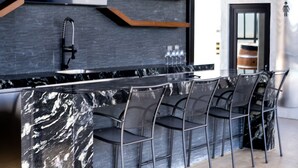 Una cocina moderna con una isla de mármol, sillas negras y un televisor de pantalla plana montado en la pared.