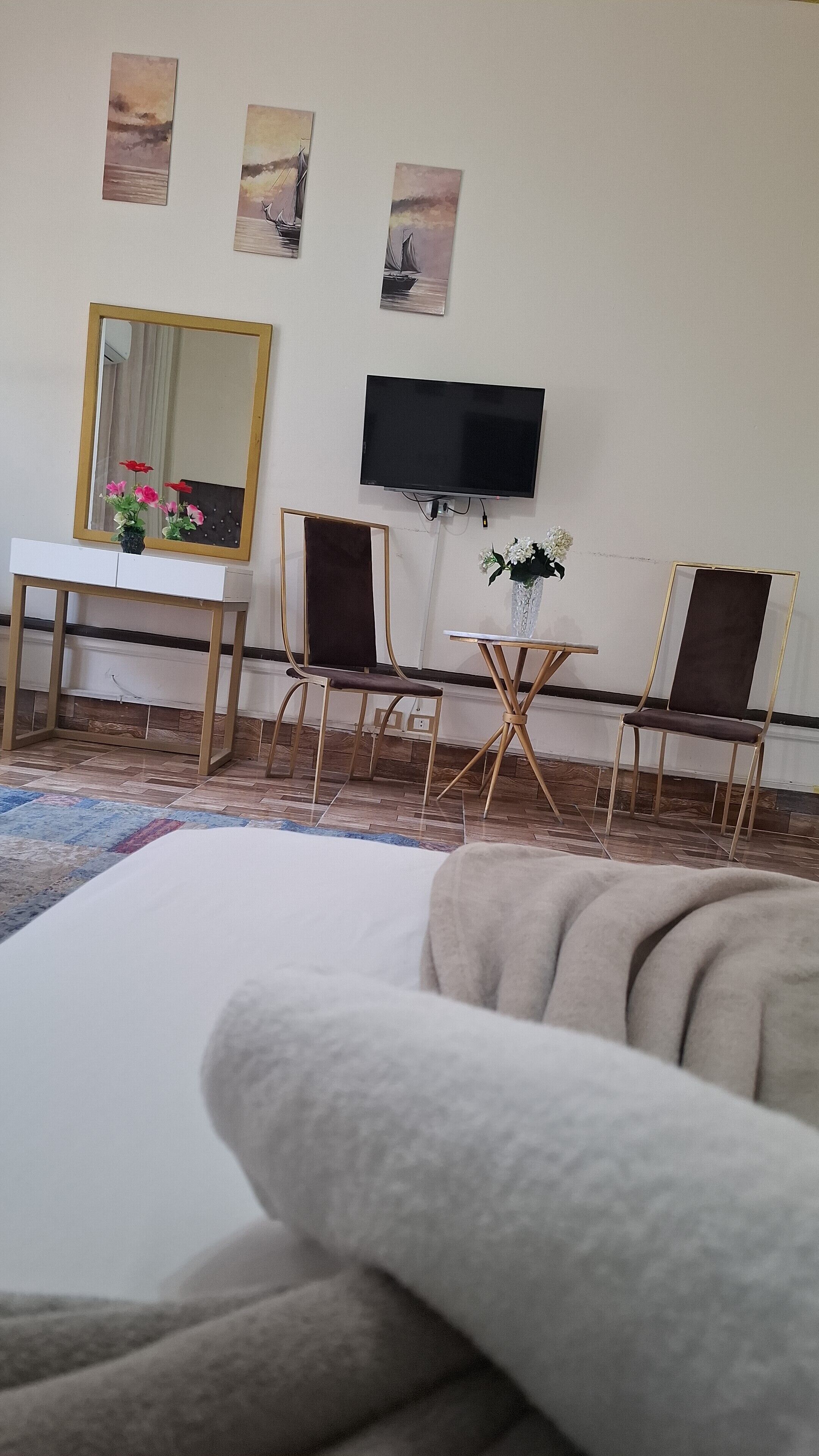 A living room with a sofa, a TV mounted on the wall, a small table with a vase, and a chair.