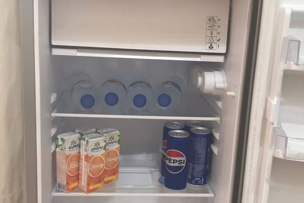 A refrigerator with shelves containing bottled water, juice cartons, and canned drinks.