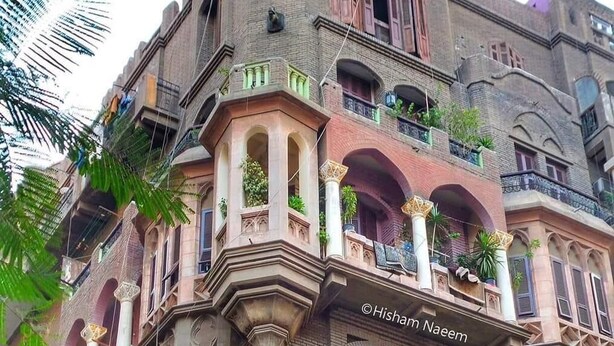 A multi-story building with ornate architectural details, including arched windows and balconies with plants. - Palace Court (Cairo)