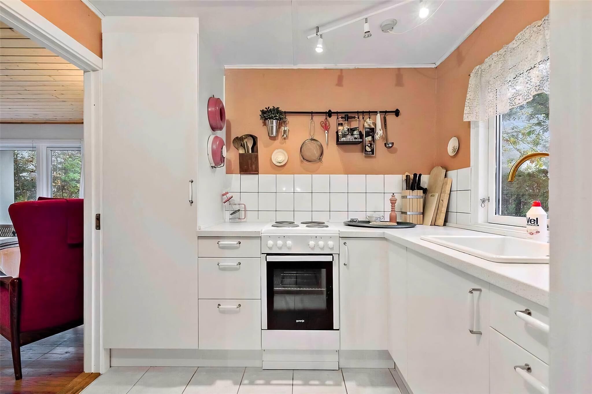 A modern kitchen with white cabinets, a built-in oven, and a window with a view of trees.