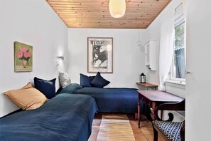 Ein Schlafzimmer mit zwei Betten, einer Holzzahlendecke, einem Poster an der Wand und einem Fenster.