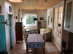 A dining area with a table and chairs, a bookshelf, a sofa, and a fireplace.