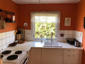 Eine Küche mit Herd, Spüle und Fenster mit Blick auf Grünfläche.