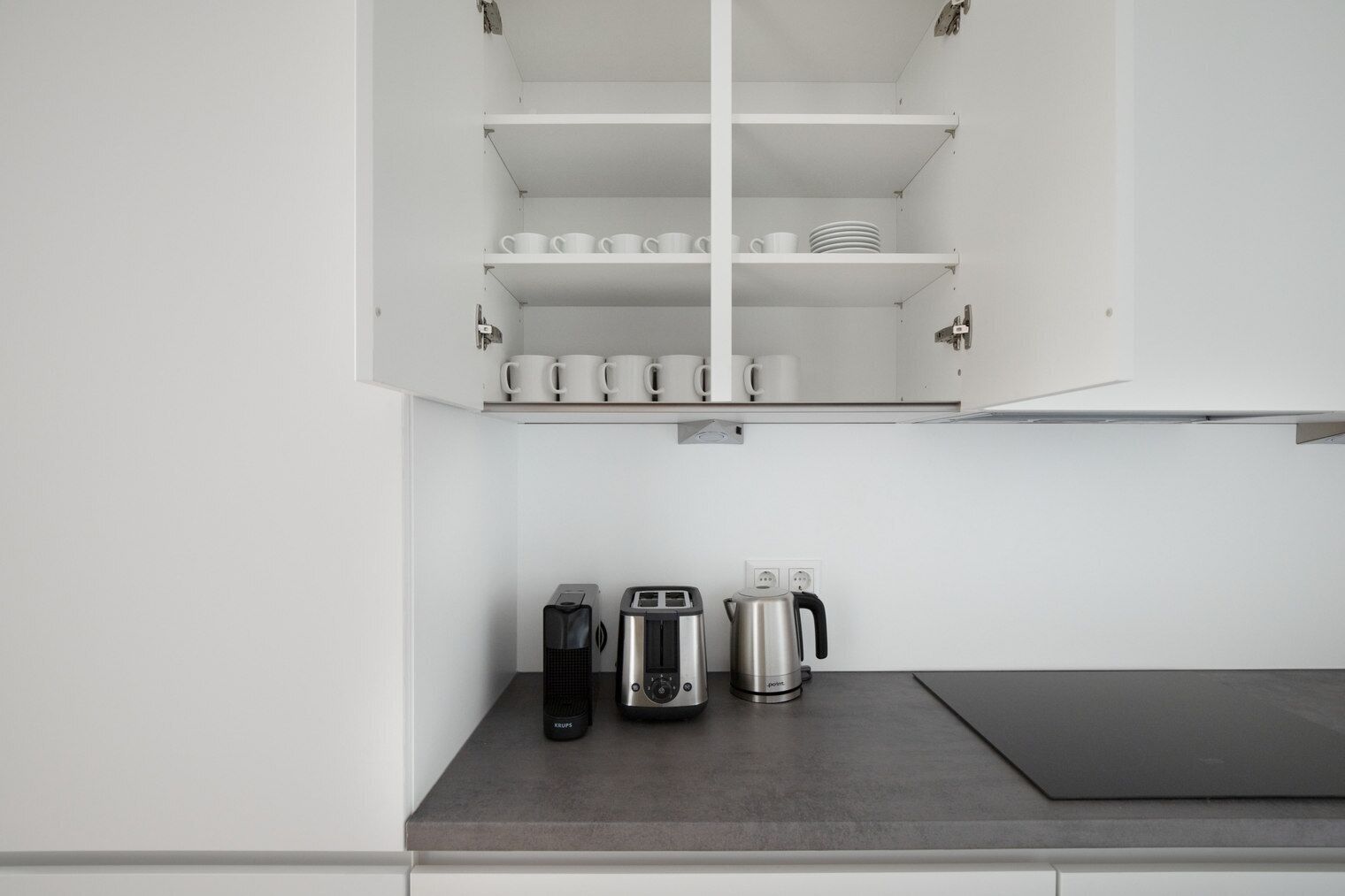 A kitchen with white cabinets, a countertop, and a coffee maker.