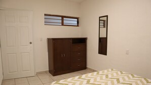 A bedroom with a bed, a wardrobe, a window, and a mirror. - Hostal Purísima (Purísima del Rincón)