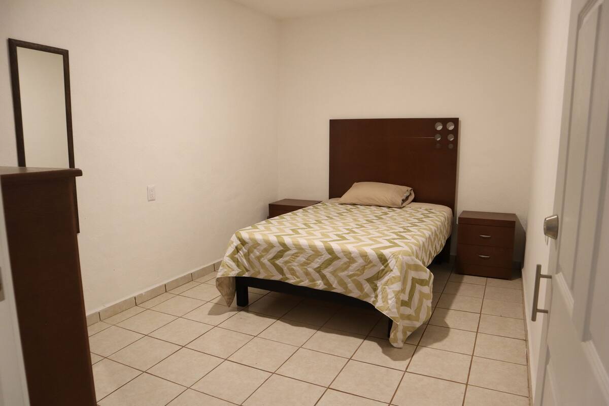 A small, clean bedroom with a bed, nightstands, and a dresser.
