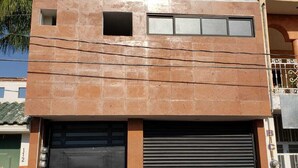 A modern building with a large garage door, a small window, and a visible door number. - Hostal Purísima (Purísima del Rincón)