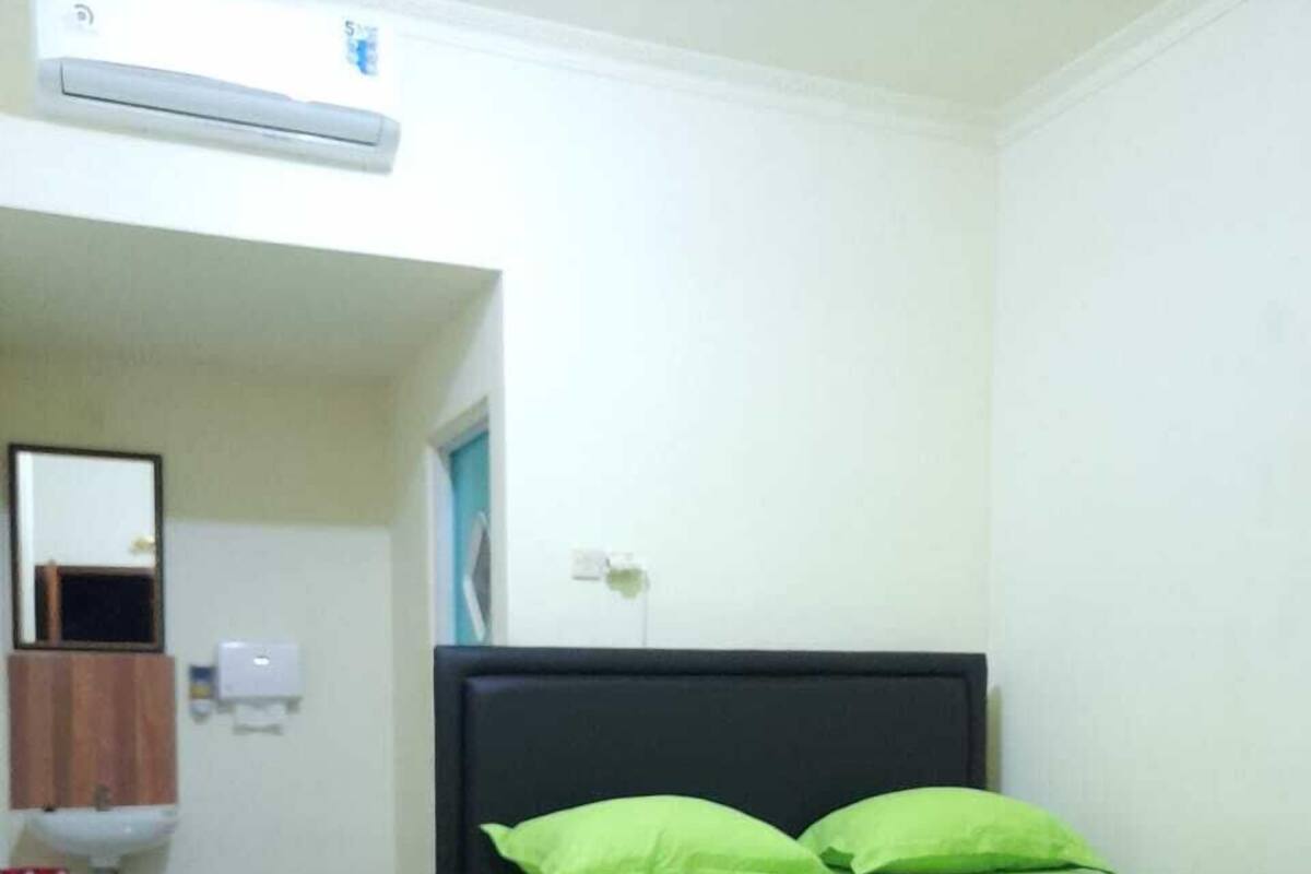 A bedroom with a bed, a mirror, a sink, and an air conditioning unit.