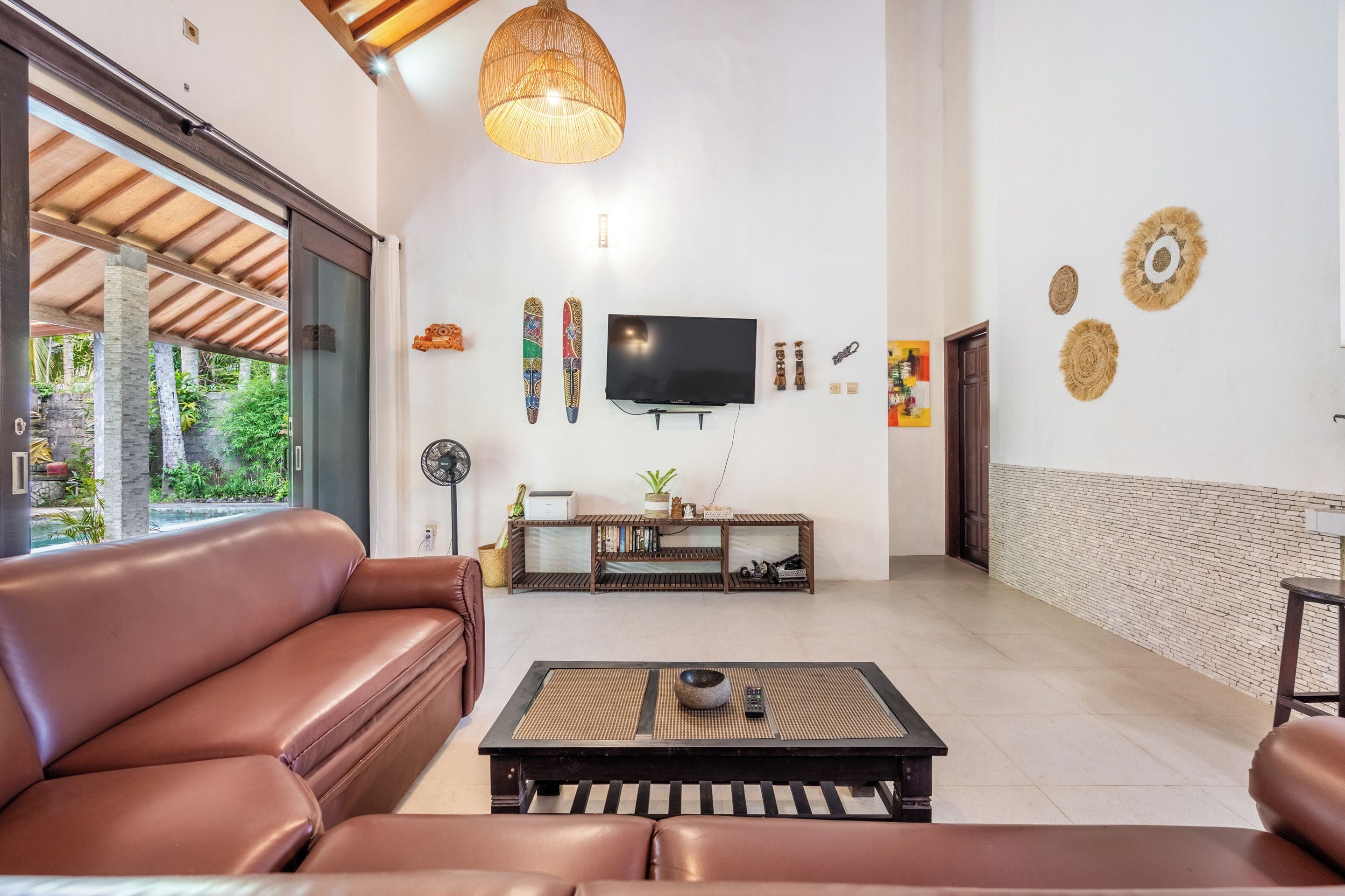 Una sala de estar con un sofá de cuero marrón, una mesa de centro, un televisor y una pared con adornos.