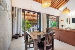 A modern kitchen with a dining area, wooden furniture, and a view of the outdoors.