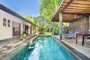 A swimming pool with a covered area and lounge chairs.