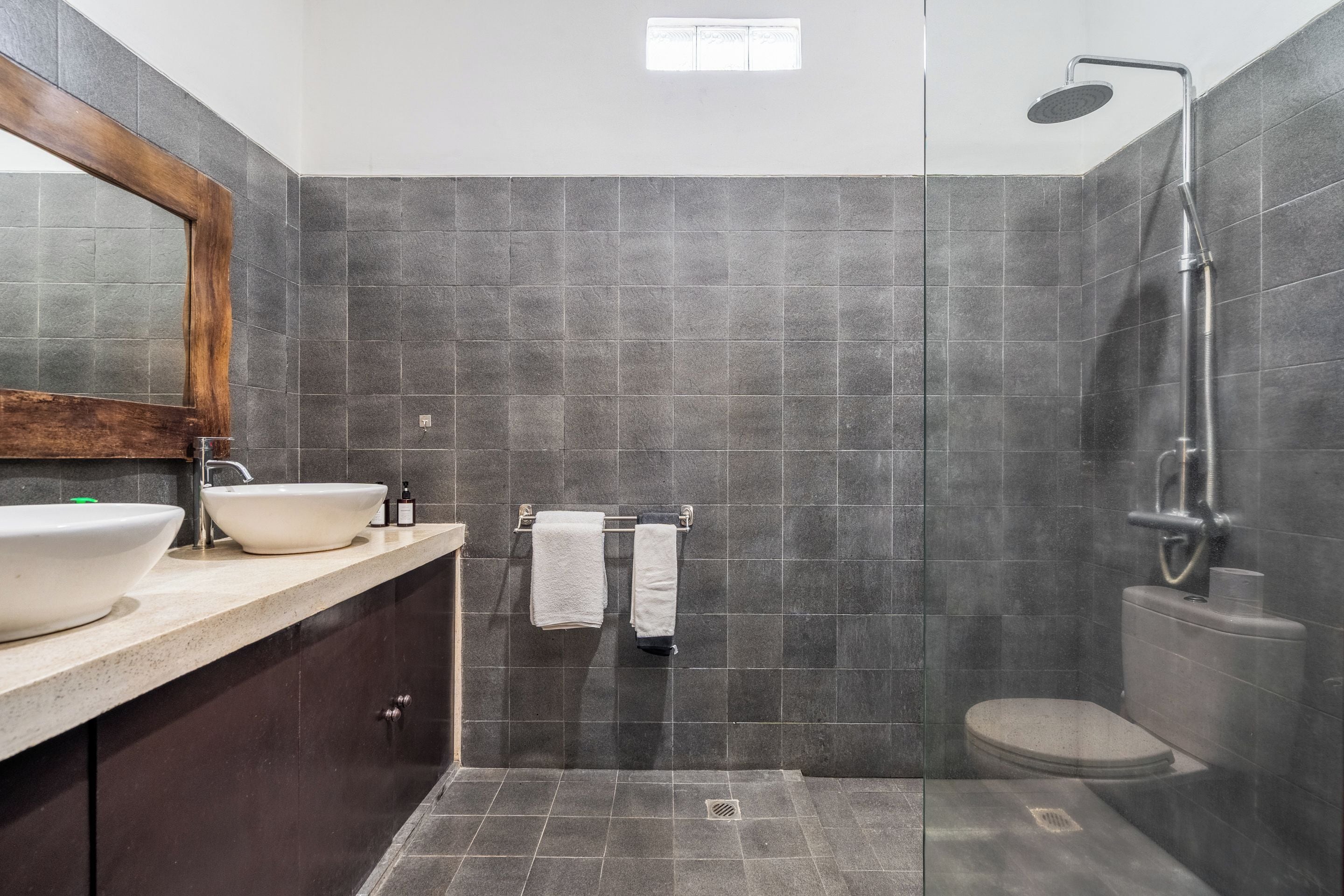 Un baño moderno con un espejo grande, un lavamanos, una ducha y un inodoro.