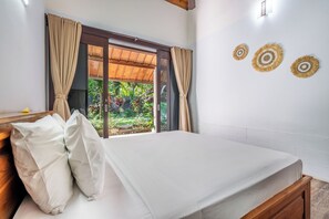 A bedroom with a bed, curtains, a window, and decorative wall art.
