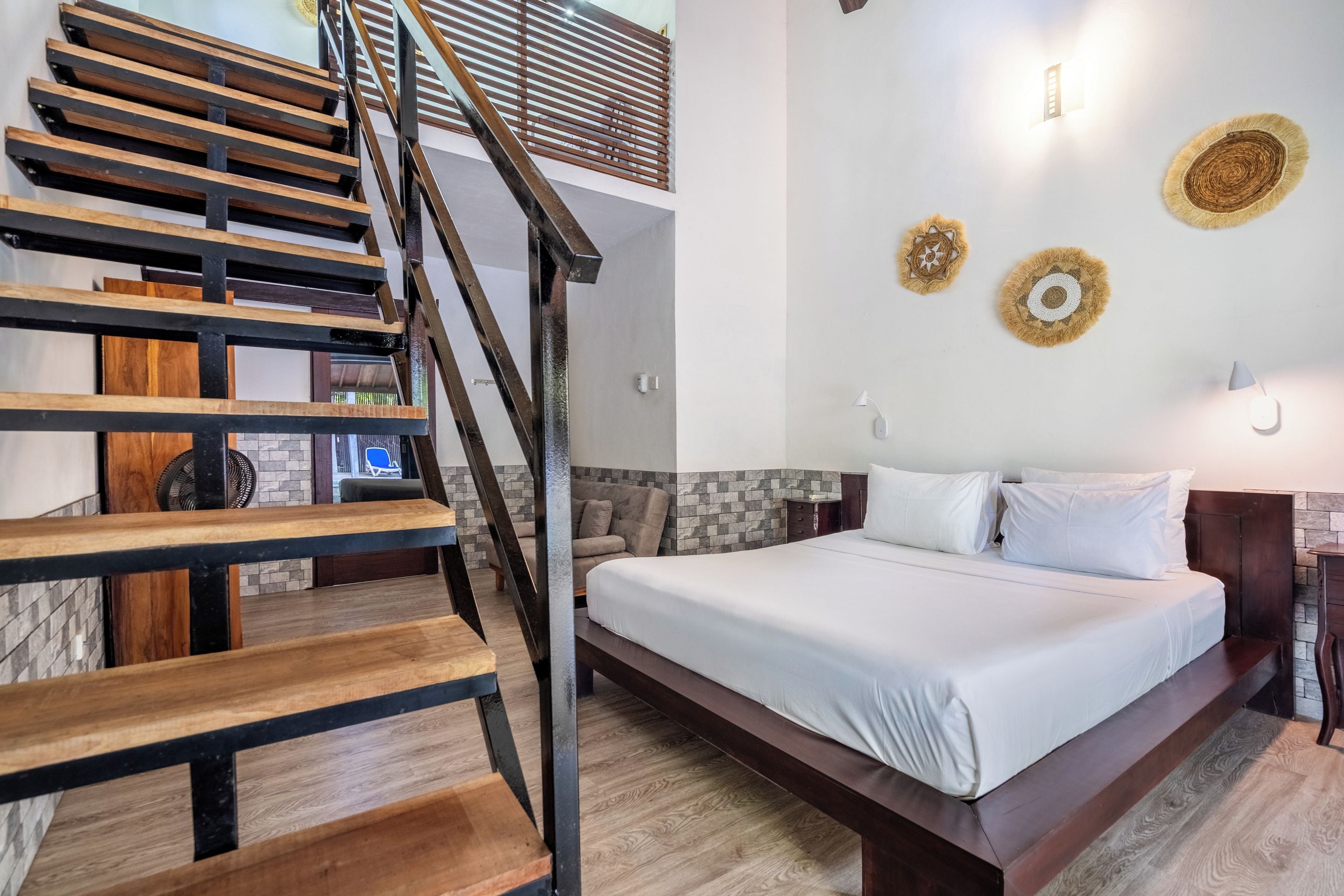 Un dormitorio con escalera de madera, cama con ropa de cama blanca y decoración mural.