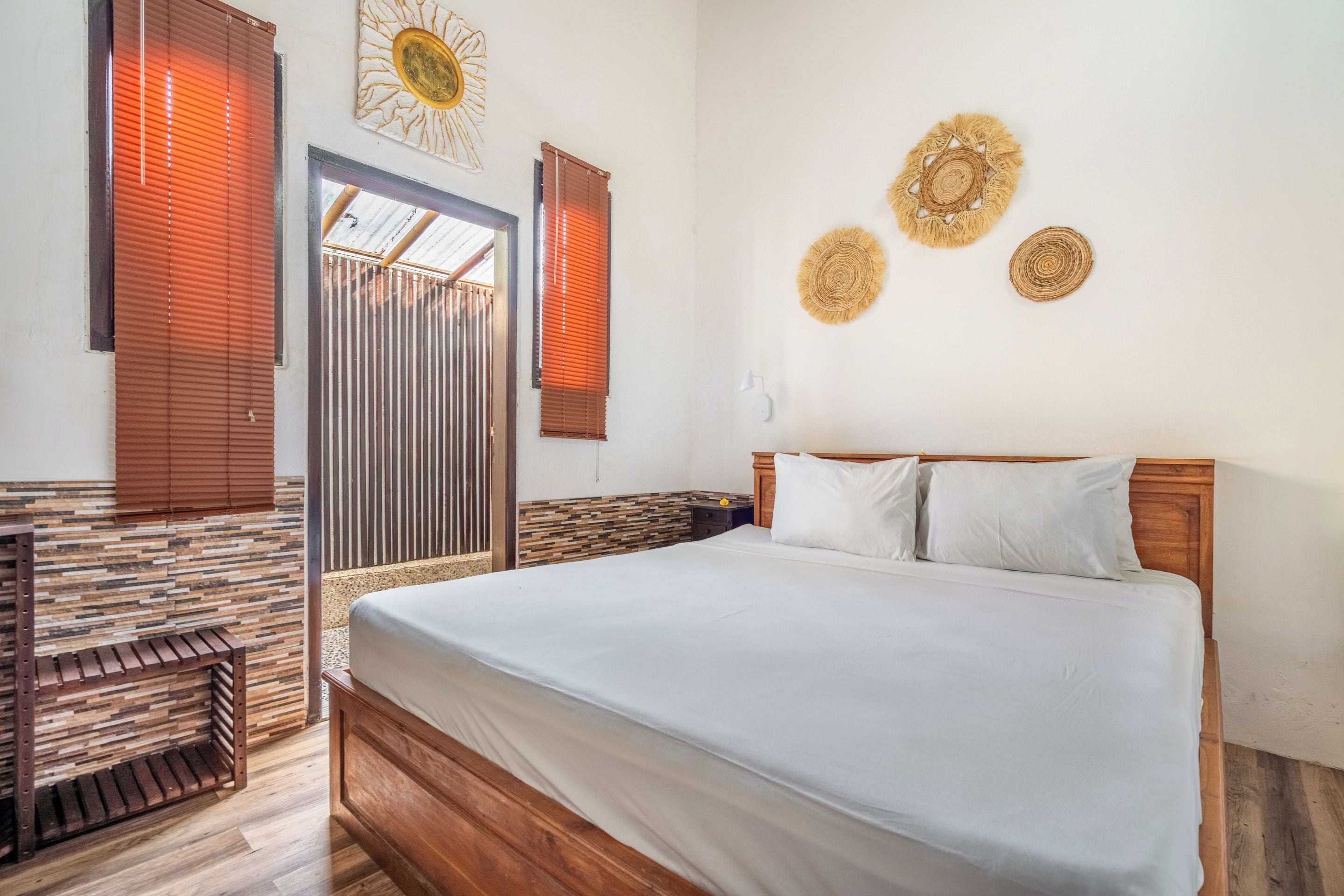 Un dormitorio con una cama de madera, una pared con estampado de piedra y una ventana con persianas.