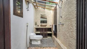 Un baño pequeño con inodoro, lavamanos y ducha.