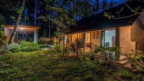 Una casa moderna con piscina, rodeada de exuberante vegetación y árboles.